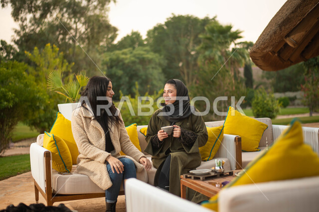 الجلوس في الهواء الطلق ، صديقتان عربيتان خليجيتان سعوديتان تستمتعان بتبادل الحديث، صداقات وتعارف ونقاشات وحوارات  قضاء أوقات ممتعة في الطبيعة الخضراء