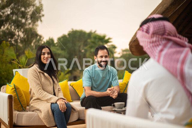 Chatting, dialogues and spending fun times with friends, a group of Saudi Gulf Arab boys and girls enjoying an exchange of conversation in a cafe in Saudi Arabia, hot drinks, chatting and dialogues, happy summer vacation