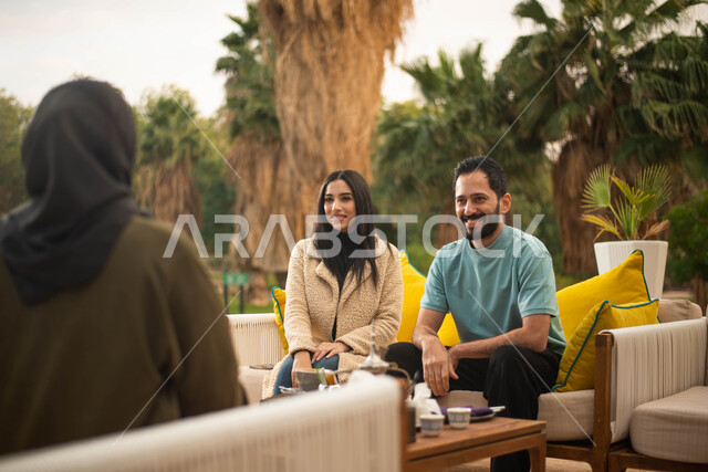 قضاء أوقات ممتعة برفقة الاصدقاء وعطلة صيفية سعيدة ، مجموعة من الشباب والبنات العرب الخليجيون السعوديون يستمتعون بتبادل الحديث في احد المقاهي في السعودية ، المشروبات الساخنة، دردشة وحوارات.