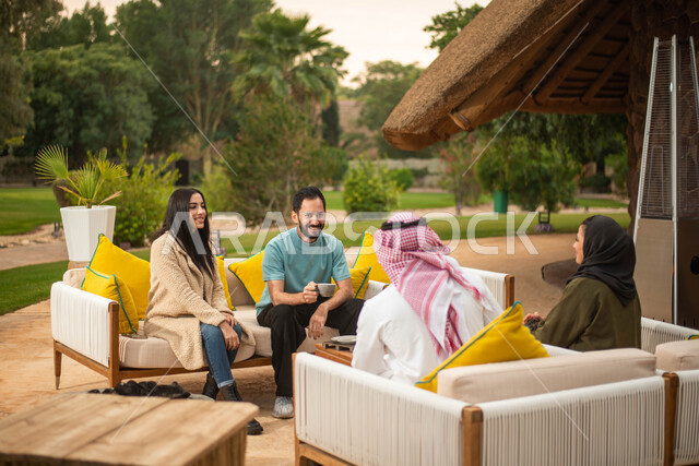 عطلة صيفية سعيدة وقضاء أوقات ممتعة برفقة الاصدقاء ، مجموعة من الشباب والبنات العرب الخليجيون السعوديون يستمتعون بتبادل الحديث في احد المقاهي في السعودية ، المشروبات الساخنة، دردشة وحوارات.