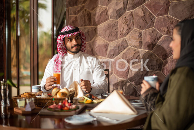 ايماءات تدل على الفرح والسعادة ،  زوجان عربيان خليجيان سعوديان يستمتعان بتناول الطعام في احد المطاعم السعودية ، نقاشات وحوارات، قضاء أوقات ممتعة في مطعم سعودي