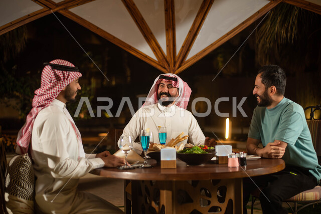 Spending fun times with friends, chatting and dialogues, a group of Saudi Gulf Arab youth enjoying an exchange of conversation in a cafe in Saudi Arabia, cold drinks, a youth session.