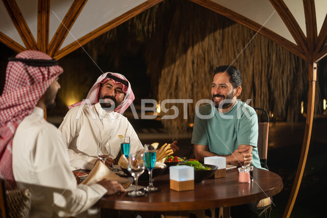 A group of Saudi Gulf Arab youth enjoying an exchange of conversation in a cafe in Saudi Arabia, cold drinks, chatting and dialogues, spending fun times with friends, a youth session.