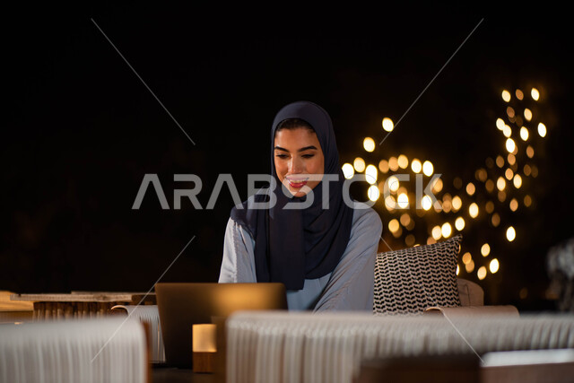 Gardens and parks, spending fun times outdoors, surfing the Internet, a Saudi Arab Gulf woman wearing the Saudi Gulf abaya using a laptop, holding a remote work meeting, completing work tasks
