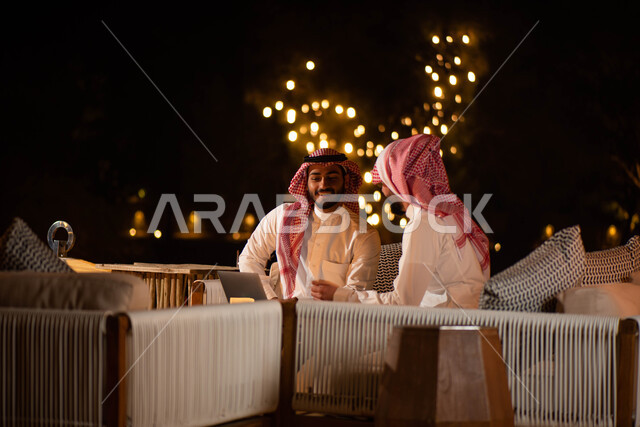  الحوارات والنقاشات ، رجلان عربيان خليجيان سعوديان يجلسان على الأريكة ، انجاز مهام العمل  عبر إستخدام جهاز الحاسوب المحمول ،  جلسات خارجية في الهواء الطلق ، اجتماع رجال الأعمال ،  تصفح الانترنت ، إستخدام أجهزة تقنية حديثة .