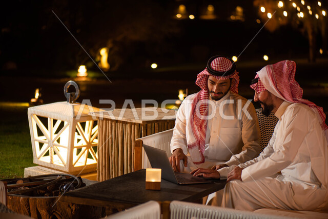  جلسات خارجية في الهواء الطلق ، اجتماع رجال الأعمال ، رجلان عربيان خليجيان سعوديان يجلسان على الأريكة ، انجاز مهام العمل  عبر إستخدام جهاز الحاسوب المحمول ،  الحوارات والنقاشات ، تصفح الانترنت ، إستخدام أجهزة تقنية حديثة .