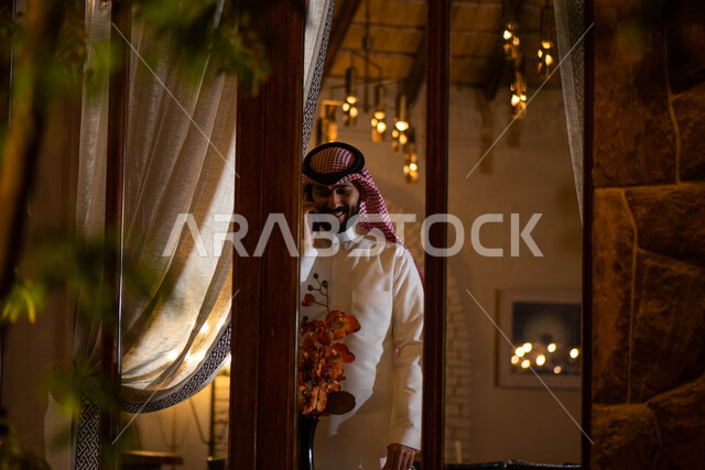التواصل مع الأصدقاء ، رجل عربي خليجي سعودي يرتدي الزي التقليدي السعودي بايماءات تدل على السعادة والسرور ، اجراء مكالمة هاتفية بإستخدام الهاتف المحمول ، مفهوم إدارة الأعمال ، إنجاز مهام ومشاريع العمل .