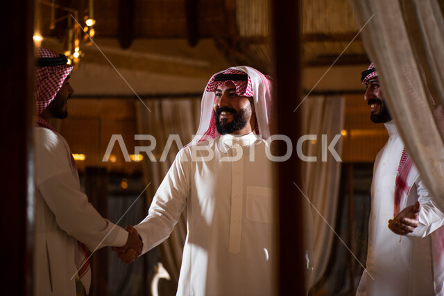 Spending fun times in the company of friends, a group of Saudi Gulf Arab men, hand gestures indicating shaking hands, saying peace and welcoming between friends, greeting and peace, agreeing on a new business deal, business partners.