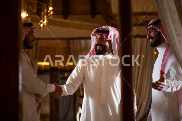 A group of Saudi Gulf Arab men, hand gestures indicating shaking hands, greeting and greeting between friends, spending pleasant times in the company of friends, greeting and peace, agreeing on a new business deal, business partners.