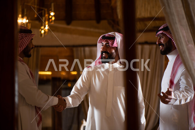 A group of young Saudi Gulf Arabs, hand gestures indicating shaking hands, greeting and greeting between friends, spending pleasant times in the company of friends, greeting and peace, agreeing on a new business deal, business partners.