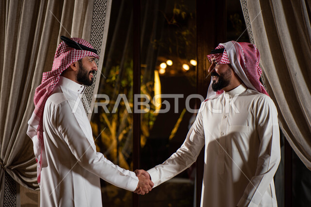 قضاء أوقات ممتعة برفقة الأصدقاء ،  رجلان عربيان خليجيان سعوديان يتصافحان بسعادة ، إلقاء السلام والترحيب بين الاصدقاء ، إيماءات يد تدل على المصافحة ، التحية والسلام ، الإتفاق على صفقة عمل جديدة ، شركاء عمل