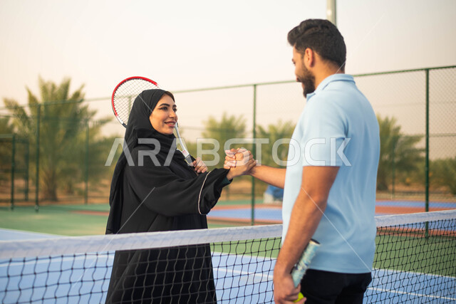 اللعب والترفيه ، زوجان عربيان خليجيان سعوديان يتصافحان استعدادا لبدء لعب كرة المضرب، ايماءات وجه تدل على الفرح والسعادة ، قضاء أوقات عائلية ممتعة ، العاب رياضية