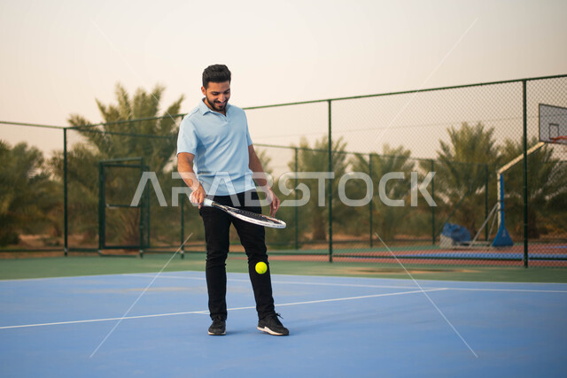 العاب رياضية في ملعب رياضي، رجل عربي خليجي سعودي يمارس كرة التنس الارضي ولعب كرة المضرب في الملاعب العامة،  تدريبات رياضية بمضرب رياضي وانشطه ترفيهيه رياضية، انشطة ورياضات شبابية نشاط بدني