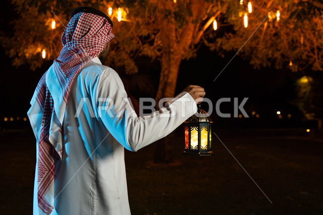إضاءة وزينة شهر رمضان، صورة خلفية لشاب عربي خليجي سعودي  يرتدي الزي السعودي التقليدي يمسك فانوس رمضان،  أجواء رمضانية، شهر رمضان المبارك، مناسبات دينية ، اسلاميات وعبادات