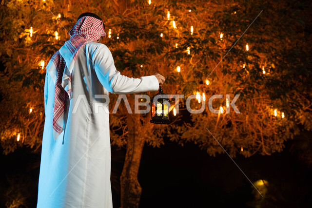 إضاءة وزينة شهر رمضان، صورة خلفية لشاب عربي خليجي سعودي  يرتدي الزي السعودي التقليدي يمسك فانوس رمضان،  أجواء رمضانية، شهر رمضان المبارك، مناسبات دينية ، اسلاميات وعبادات
