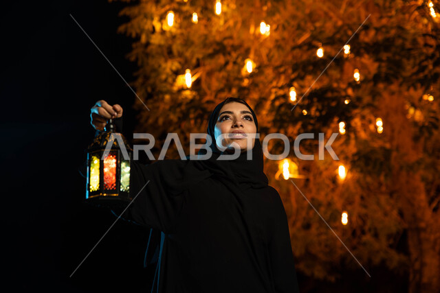 شهر رمضان المبارك، إضاءة وزينة شهر رمضان، امرأة عربية خليجية سعودية ترتدي العباءة الخليجية السعودي تمسك فانوس رمضان،  أجواء رمضانية، مناسبات دينية ، اسلاميات وعبادات