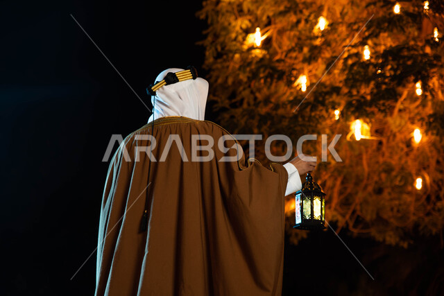 The Saudi founding day, a background image of a Saudi Arab Gulf youth wearing traditional folk costume, holding a Ramadan lantern in his hand, the Saudi National Day, heritage and folklore, lighting and decorations for the month of Ramadan, Ramadan atmosp