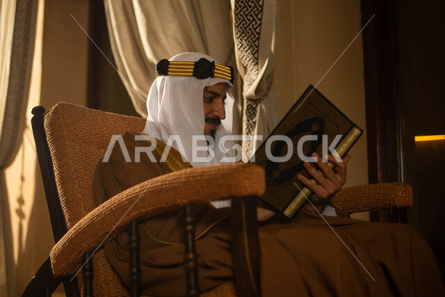 رجل عربي خليجي سعودي يرتدي زي تراثي شعبي سعودي ويمسك المصحف الشريف، قراءة وتلاوة القرآن الكريم، حفظ القران الكريم، ذكر الله، يوم التأسيس السعودي