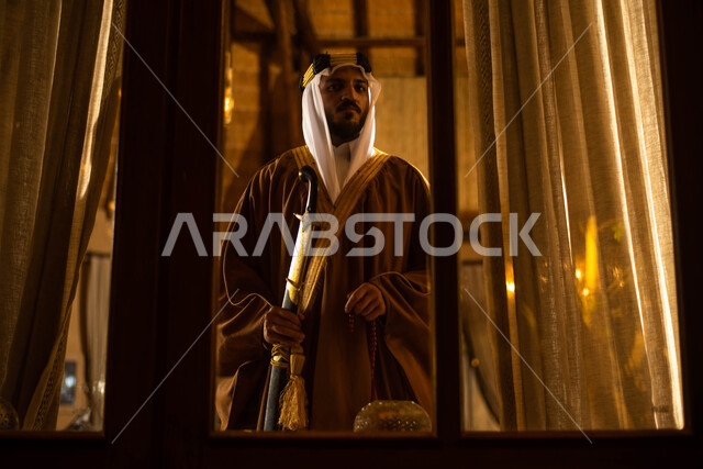 يوم التاسيس السعودي ، رجل عربي سعودي خليجي يرتدي الزي التراثي الشعبي التقليدي،  يمسك بيده السيف ، النظر الى شيء ما،  اليوم الوطني السعودي، تراثيات وشعبيات