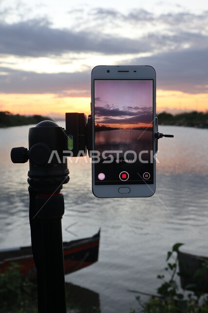 التقاط صورة تذكارية من خلال الكاميرا الخلفية للهاتف المحمول، هاتف محمول على حامل تثبيت الهواتق والكاميرات، الاشجار والنباتات الخضراء المحيطة بالبحيرة المائية، مناظر طبيعية، خلفية الطبيعة