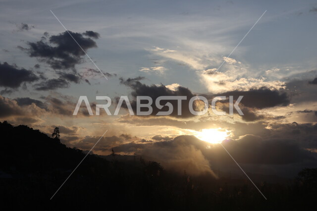Silhouette of mountains and highlands at sunset, bright sunlight from behind clouds and clouds, landscapes, nature background