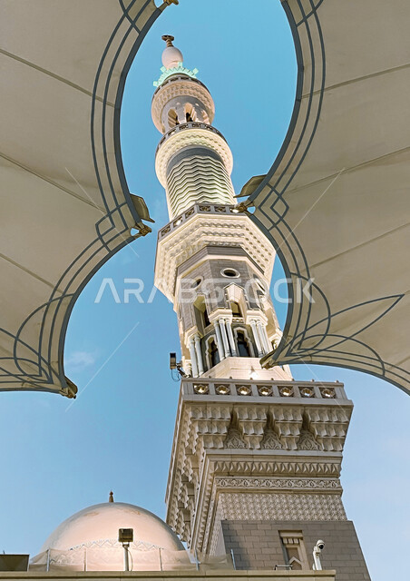 A close-up of an electronic umbrella and the minaret of the Prophet's Mosque in Medina in the Kingdom of Saudi Arabia, the Prophet's Mosque, landmarks of the Prophet's Mosque, electronic umbrellas in the Prophet's Mosque in Medina, worship and closeness t