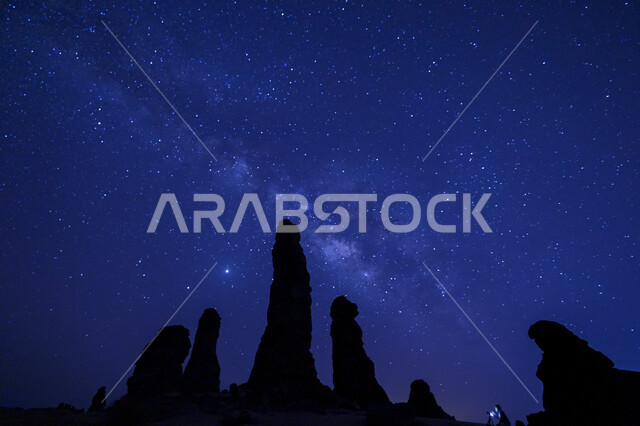 صورة ظلية للتكوينات الصخرية في العلا في المملكة العربية السعودية ليلا، مجرة درب التبانة مع الشهب والنجوم في السماء، معالم اثرية تاريخية قديمة، اماكن سياحية في السعودية