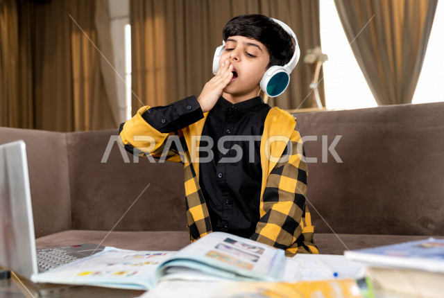 A Saudi Gulf student wearing a headset, studying at home with different facial expressions, following online classes via a laptop, distance learning, the concept of online education, home education during quarantine and the outbreak of the Corona virus, s