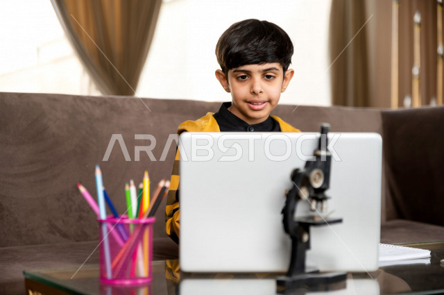 تلميذ سعودي خليجي يدرس في المنزل بتعابير وجه مختلفة ، يتابع حصص الاونلاين عن طريق الحاسوب المحمول  ، التعلم عن بعد ، مفهوم التعليم عبر الانترنت ، التعليم المنزلي اثناء الحجر الصحي و تفشي فيروس كورونا ، العزلة الذاتية 