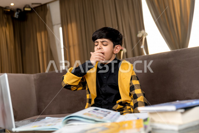 تلميذ سعودي خليجي يدرس في المنزل بتعابير وجه مختلفة ، يتابع حصص الاونلاين عن طريق الحاسوب المحمول  ، التعلم عن بعد ، مفهوم التعليم عبر الانترنت ، التعليم المنزلي اثناء الحجر الصحي و تفشي فيروس كورونا ، العزلة الذاتية .