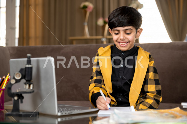 تلميذ سعودي خليجي يدرس في المنزل بتعابير وجه مختلفة ، يتابع حصص الاونلاين عن طريق الحاسوب المحمول  ، التعلم عن بعد ، مفهوم التعليم عبر الانترنت ، التعليم المنزلي اثناء الحجر الصحي و تفشي فيروس كورونا ، العزلة الذاتية 