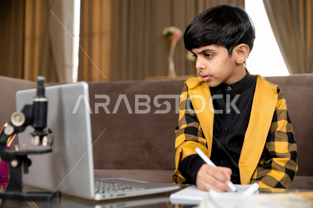 تلميذ سعودي خليجي يدرس في المنزل بتعابير وجه مختلفة ، يتابع حصص الاونلاين عن طريق الحاسوب المحمول  ، التعلم عن بعد ، مفهوم التعليم عبر الانترنت ، التعليم المنزلي اثناء الحجر الصحي و تفشي فيروس كورونا ، العزلة الذاتية 