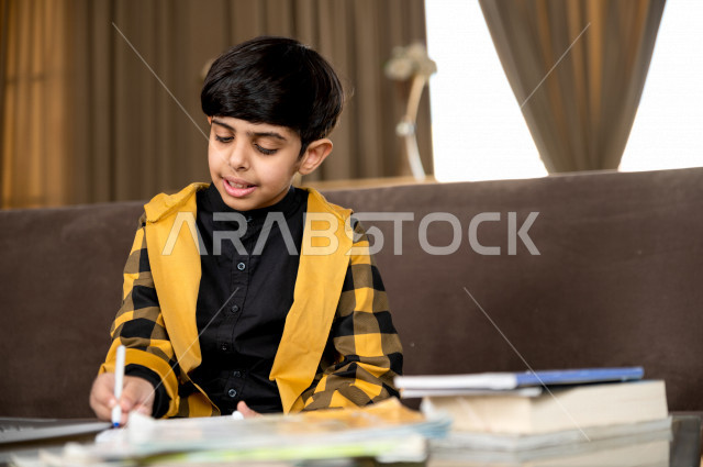 تلميذ سعودي خليجي يدرس في المنزل و يؤدي واجباته المدرسية ، التعليم عن بعد ، مفهوم التعليم عبر الانترنت ، التعليم المنزلي اثناء الحجر الصحي و تفشي فيروس كورونا ، العزلة الذاتية .