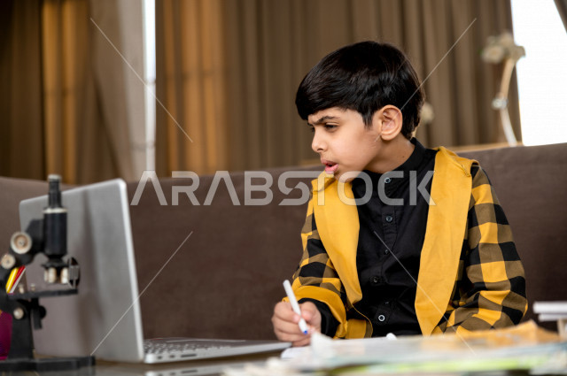 تلميذ سعودي خليجي يدرس في المنزل بتعابير وجه مختلفة ، يتابع حصص الاونلاين عن طريق الحاسوب المحمول  ، التعلم عن بعد ، مفهوم التعليم عبر الانترنت ، التعليم المنزلي اثناء الحجر الصحي و تفشي فيروس كورونا ، العزلة الذاتية 