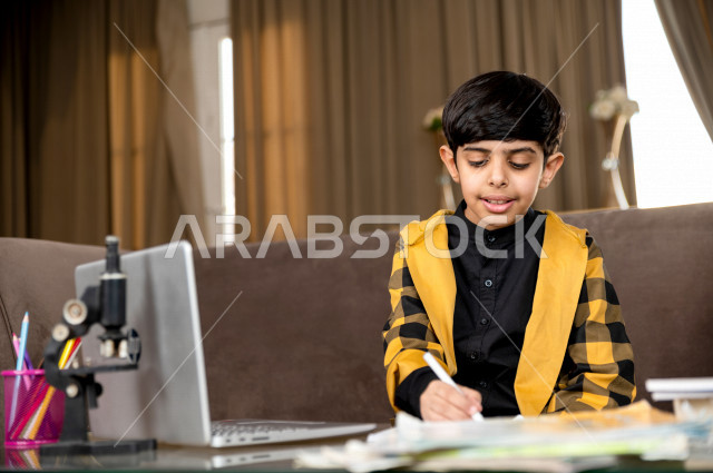 A Saudi Gulf student studying at home with different facial expressions, following online classes via a laptop, distance learning, the concept of online education, home education during quarantine and the outbreak of the Corona virus, self-isolation