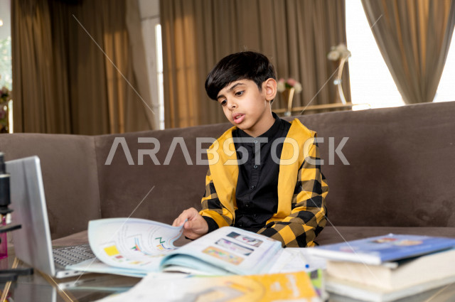 تلميذ سعودي خليجي يدرس في المنزل بتعابير وجه مختلفة ، يتابع حصص الاونلاين عن طريق الحاسوب المحمول  ، التعلم عن بعد ، مفهوم التعليم عبر الانترنت ، التعليم المنزلي اثناء الحجر الصحي و تفشي فيروس كورونا ، العزلة الذاتية 