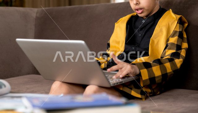 A Saudi Gulf student studying at home with different facial expressions, following online classes via a laptop, distance learning, the concept of online education, home education during quarantine and the outbreak of the Corona virus, self-isolation