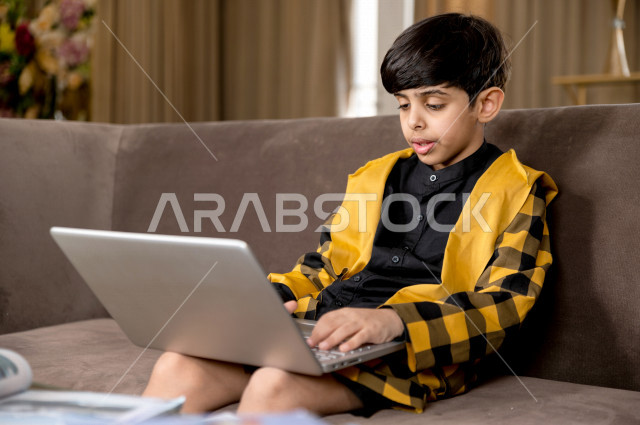 تلميذ سعودي خليجي يدرس في المنزل بتعابير وجه مختلفة ، يتابع حصص الاونلاين عن طريق الحاسوب المحمول  ، التعلم عن بعد ، مفهوم التعليم عبر الانترنت ، التعليم المنزلي اثناء الحجر الصحي و تفشي فيروس كورونا ، العزلة الذاتية 