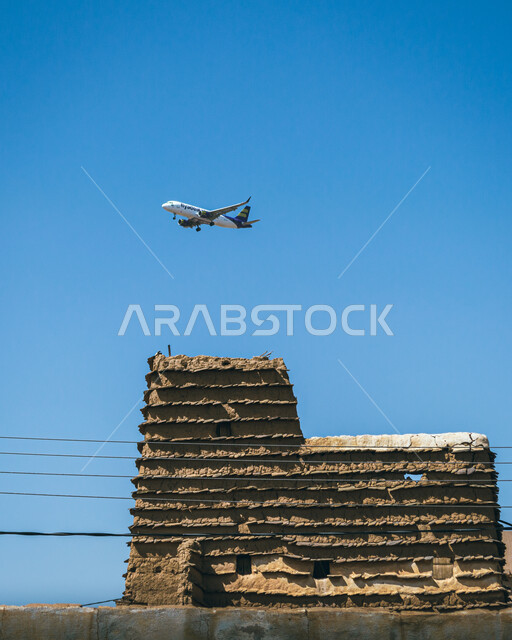A Saudi Arabian Airlines plane flying over ancient mud houses in Asir, Saudi Arabia, ancient historical and archaeological landmarks, Saudi Air Force, historical villages and cities, old houses, ancient Arab architecture