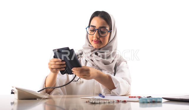 استخدام جهاز قياس ضغط الدم, العمل في القطاع الطبي,  بورتريه لطبيبة عربية خليجية سعودية محجبة ترتدي المعطف الطبي الابيض والنظارات الطبية , تقديم الاستشارات الطبية والخدمات, خلفية بيضاء