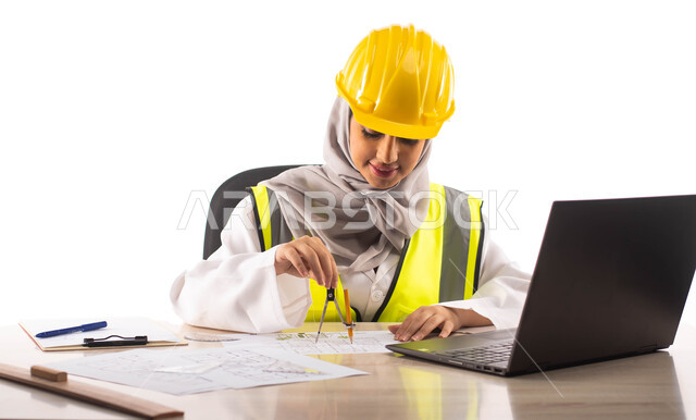 استخدام الفرجار الهندسي و الأدوات والمعدات على مخطط تصميم هندسي ، ارتداء بدلة السلامة وخوذة الوقاية الصفراء, بورتريه لمهندسة معمارية عربية خليجية سعودية محترفه ومبتسمة داخل مكتب هندسي ، خلفية بيضاء