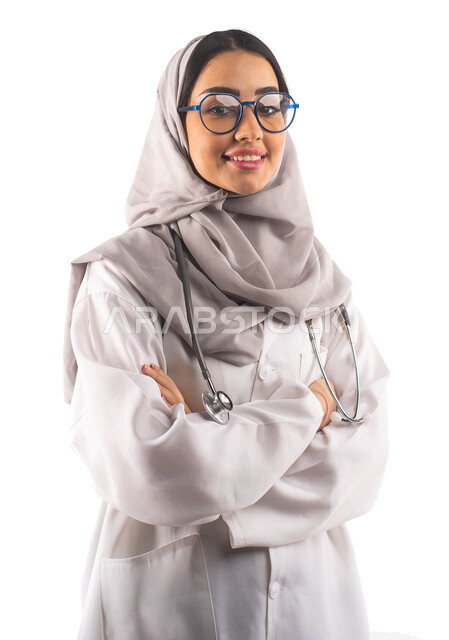  ارتداء النظارات الطبية و المعطف الطبي , الاستعداد لتقديم الخدمات ،العمل في القطاع الصحي, بورتريه لطبيبة عربية سعودية خليجية محجبة مكتفة اليدين, مفهوم الطب والرعاية الصحية ، مهن و وظائف ، خلفية بيضاء