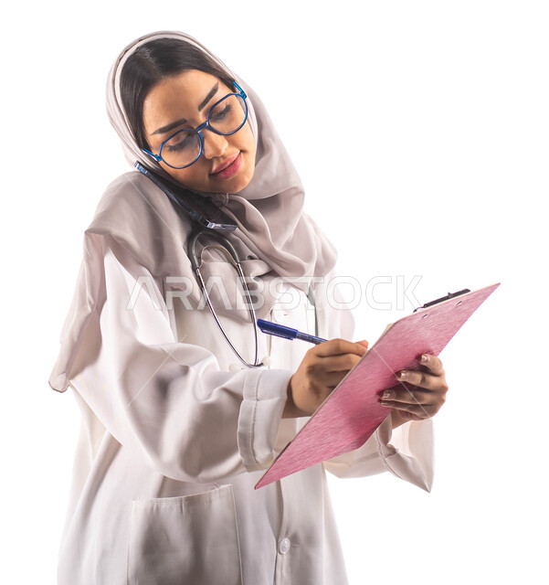 اجراء مكالمة هاتفيه عبر الجوال, تسجيل البيانات على ملف تشخيص المريض, العمل في القطاع الصحي, بورتريه لطبيبة عربية سعودية خليجية محجبة ومبتسمة, تحمل بيدها ملف خاص بالمرضى، ارتداء المعطف الطبي والنظارات الطبية, مفهوم الطب والرعاية الصحية ، مهن و وظائف  ، خلف
