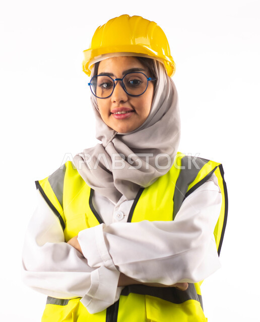 تصاميم ومخططات هندسية، الاستعداد للعمل, بورتريه لمهندسة انشاءات معمارية عربية سعودية خليجية مكتفة اليدين ، ارتداءالخوذة وبدلة السلامة الخاصة في العمل ، مهن ووظائف ، خلفية بيضاء