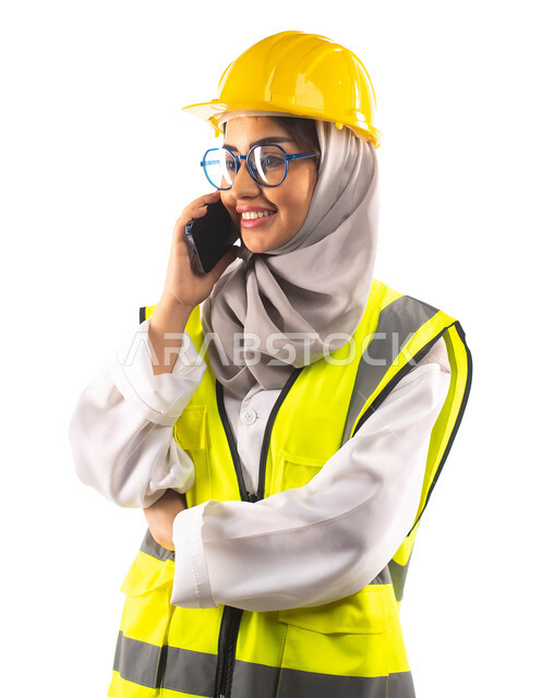 Making a phone call via mobile, gestures indicating happiness and joy, a portrait of a smiling Saudi Arabian Gulf construction engineer wearing medical glasses, wearing a helmet and a special safety suit at work, engineering plans and designs, professions