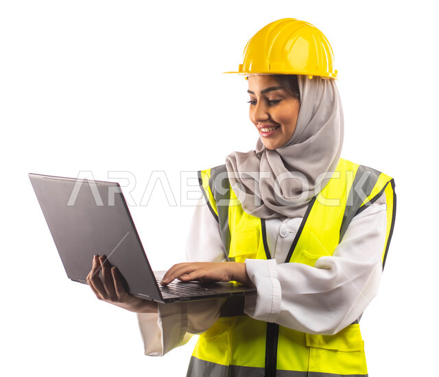 ايماءات تدل على السرور والفرح, تحمل بيدها الحاسوب المحمول, بورتريه  لمهندسة انشاءات معمارية عربية سعودية خليجية مبتسمة،  ارتداءالخوذة وبدلة السلامة الخاصة في العمل ،مخططات وتصاميم هندسية، مهن ووظائف ، خلفية بيضاء