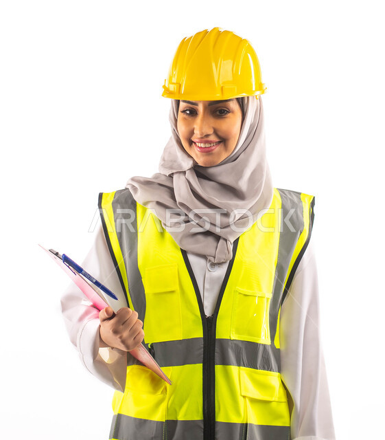 ايماءات تدل على الفرح والسعادة, مهن و وظائف هندسية، ادارة المشاريع الهندسية، بورتريه لمهندسة معمارية عربية خليجية سعودية محترفة ترتدي خوذة وسترة الحماية الخاصة بالعمل، تحمل بيدها ملف خاص بالعمل،  مخططات و تصماميم هندسية