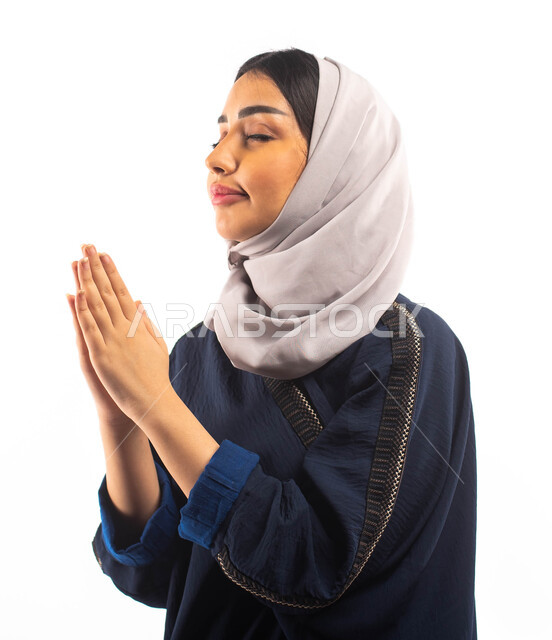 إيماءات وجه ويدين تدل على الدعاء والتضرع الى الله,  بورتريه لامرأة عربية خليجية سعودية محجبة, طلب العون والمغفرة , الرغبه في تحقيق الأمنيات, خلفية بيضاء .