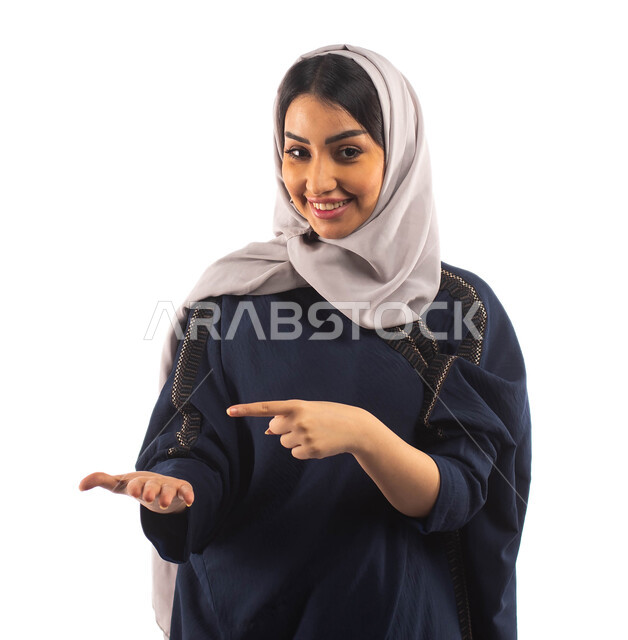 ايماءات يدين تشير الى شيء ما, النظر الى الكاميرا, بورتريه لأمرأه عربية خليجية سعودية محجبة ترتدي العباءة السوداء, استخدام حاسة اللمس لتحريك العناصر الهولوجراميه, النقر على الشاشه, الشعور بالإعجاب والرضى, البهجه والسرور, خلفية بيضاء