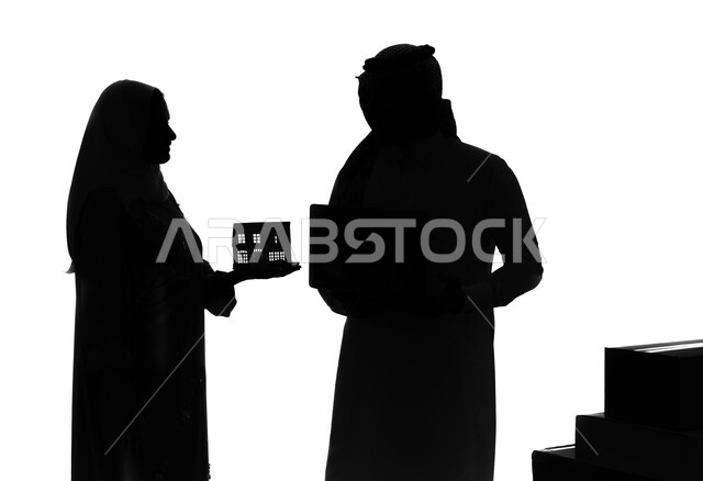 مشاركة الزوجين في اختيار منزل الأحلام, زوج سعودي يقوم بتصفح مواقع العقارات الالكترونية, شراء عقار جديد عبر الاونلاين, بورتريه صورة ظلية لإمرأة عربية خليجية سعودية تحمل مجسم لبيت صغير تقف بجانب زوجها، اسكان وتمليك، خلفية بيضاء, سيلوليت